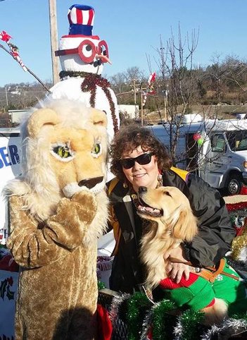 Leader Dog Jemma and author Ronda Del Boccio on the Lions Club float. Behind them, a Snowman wears glasses. Beside them is the mascot Lion.